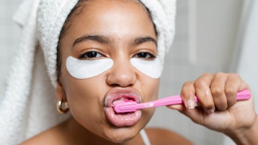 Woman Brushing Her Teeth With White Bath Towel On Head