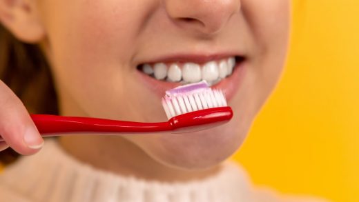 girl with red and white toothbrush in mouth